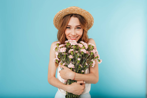 Image of young happy caucasian woman isolated over blue background holding flowers. - Zdjęcie, obraz
