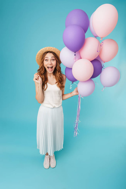 Image of young emotional screaming caucasian woman isolated over blue background holding balloons. - Φωτογραφία, εικόνα