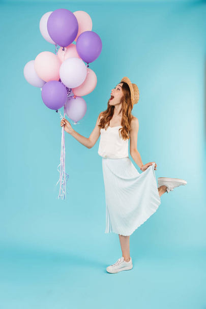 Image of young excited caucasian woman isolated over blue background holding balloons. - Фото, зображення