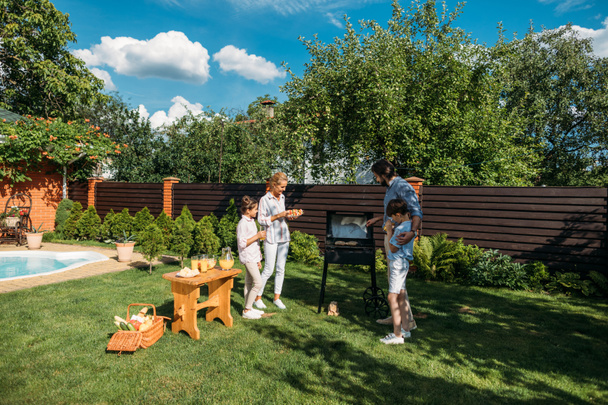 οικογένεια έχοντας μαζί μπάρμπεκιου στην πίσω αυλή, καλοκαιρινή μέρα - Φωτογραφία, εικόνα
