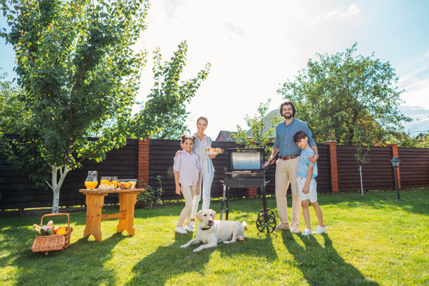 family with dog having barbecue together on backyard on summer day - Foto, Imagem