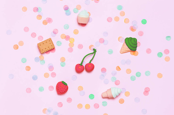 Fun holiday background with various confetti and little tasty figures of fruits and desserts. - Photo, image