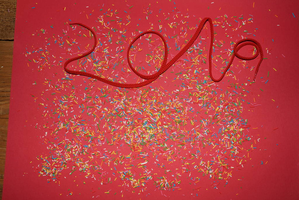 number 2019 of red rope on red background with colorful confetti. Christmas theme.  - Photo, image