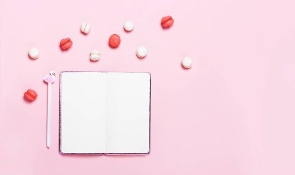 Empty notebook with macarons on pink background. Blogger still life. Flat lay, top view - Zdjęcie, obraz