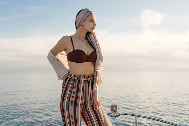 confident attractive young woman in stylish pants posing against the sea in the sun - Foto, imagen