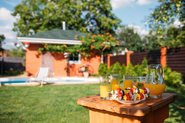 selective focus of fresh vegetables for barbecue and glasses of juice on backyard - Foto, imagen