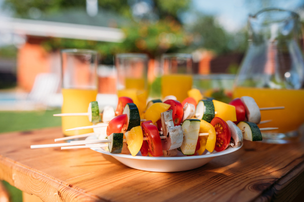 close up view of fresh vegetables for barbecue and glasses of juice on backyard - Fotoğraf, Görsel