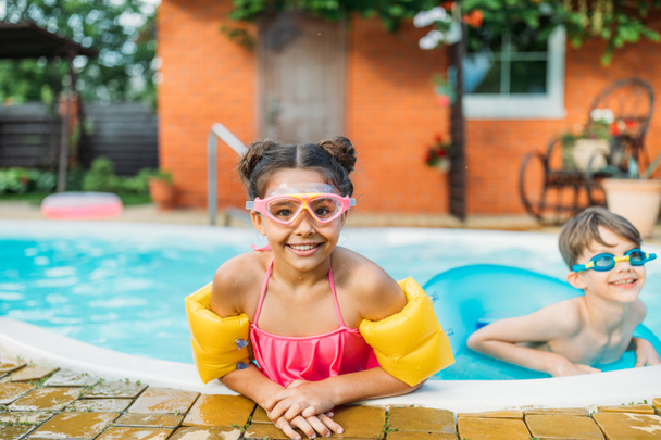 портрет маленьких братьев и сестер, плавающих в бассейне вместе в летний день
 - Фото, изображение