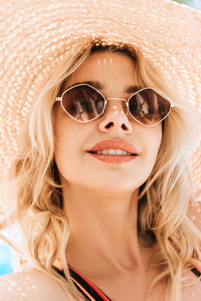 portrait of beautiful smiling young blonde woman in sunglasses and wicker hat - Foto, Bild