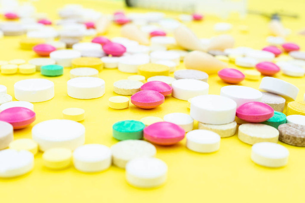 Assorted pharmaceutical medicine pills, tablets and capsules over yellow background - 写真・画像