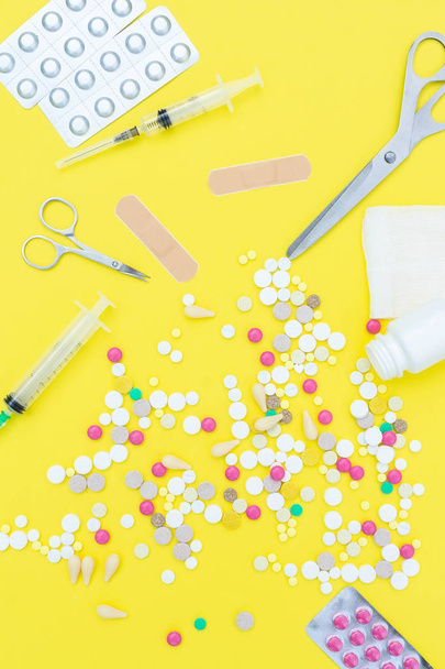 Assorted pharmaceutical medicine pills, tablets and capsules over yellow background - 写真・画像