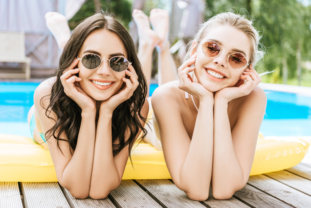 belles jeunes femmes allongées sur un matelas gonflable et souriant à la caméra au bord de la piscine
 - Photo, image
