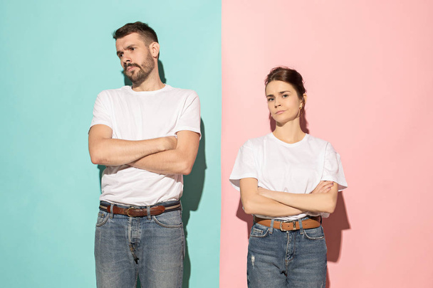 The serious man and woman looking at camera against pink and blue background. - Фото, изображение