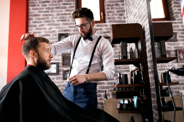 Hairdresser adjusts hair a customer in barbershop salon - Valokuva, kuva