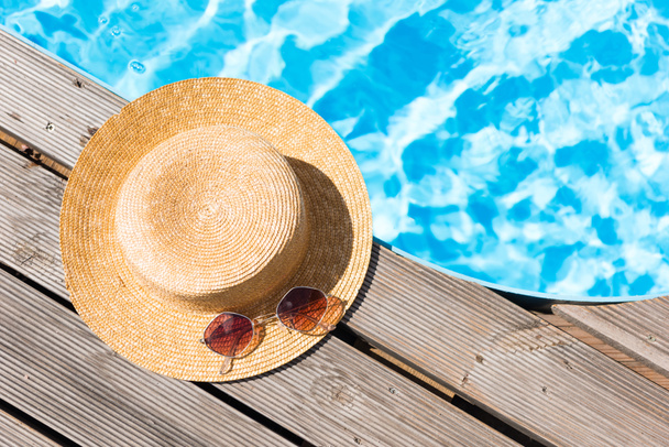 vista de cerca del sombrero de mimbre y gafas de sol cerca de la piscina
   - Foto, imagen