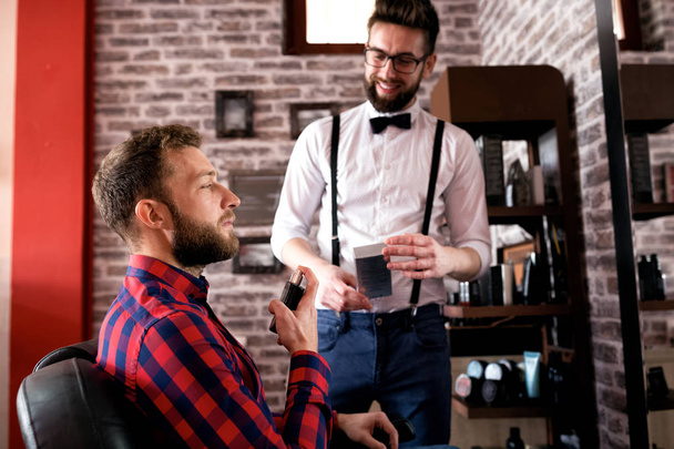 Customer spray perfume on beard after treatment in barbershop salon - Foto, Bild