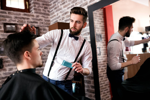 Hairdresser adjusts hair a customer with a gel in barbershop salon - Foto, imagen