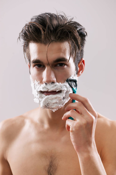 Young handsome man is shaving his beard.  - Foto, Bild
