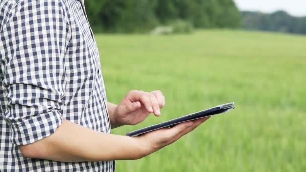 The caucasian male brunette farmer on the field works with a tablet. Scientist working in the field with agricultural technology. - Metraje, vídeo