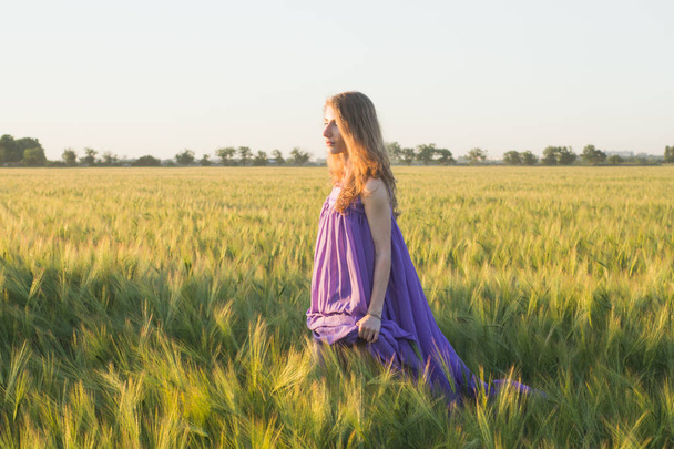 Fiatal gyönyörű nőt walking, nyári búza mezők durinf naplemente - Fotó, kép