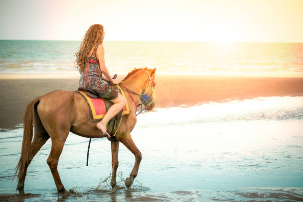Woman fashion model riding a horse on the beach in summer. Luxury travel vacation. - Photo, Image
