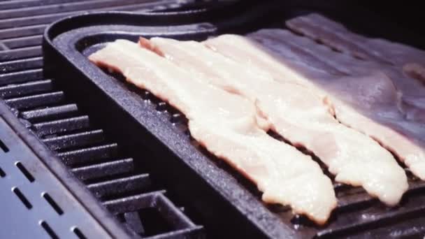 Grillen bacon reepjes op gietijzeren grillplaat in buiten gas barbecue - Video