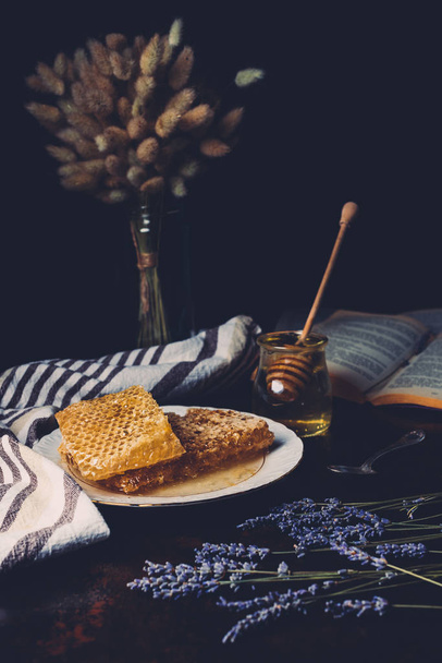 enfoque selectivo de panales en placa, lavanda y frasco con palo de miel sobre fondo negro
  - Foto, Imagen