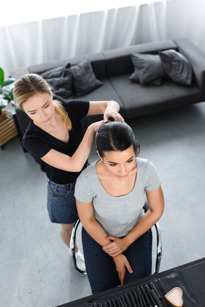 overhead view of hairstylist doing hairstyle to young woman on chair - Photo, Image