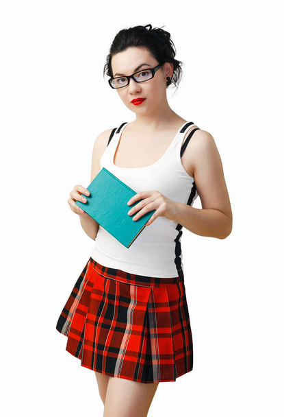 Женщина в костюме школьницы и черных очках для чтения держит книгу в руках. Изолированный на белом фоне
 - Фото, изображение