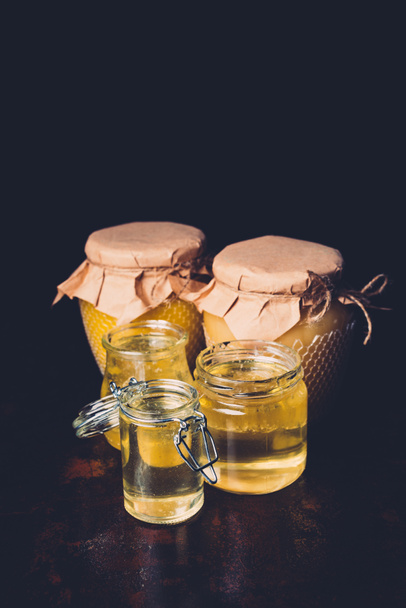 enfoque selectivo de diferentes frascos con miel sobre fondo negro
  - Foto, imagen