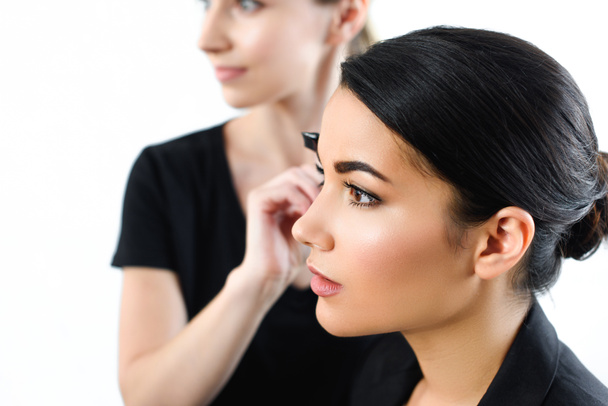 selective focus of young businesswoman getting makeup done by makeup artist - Photo, Image