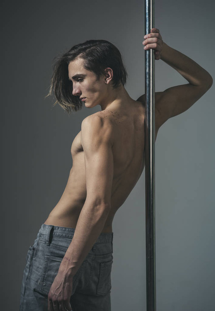 Young strong pole dance man in grey sudio. - Foto, Imagem