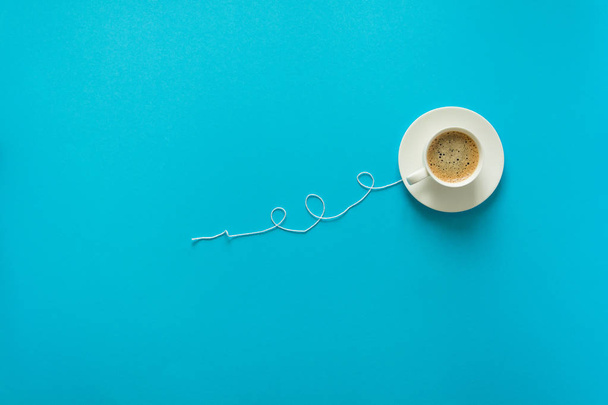 Coffee cup in shape of balloon with clouds on blue paper background. - Fotó, kép