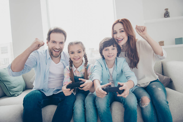 Portrait of cheerful brother and sister playing x-box using console controller active mom dad with raised fists celebrating victory shouting enjoying video game. Motivation inspiration concept - Foto, Imagen