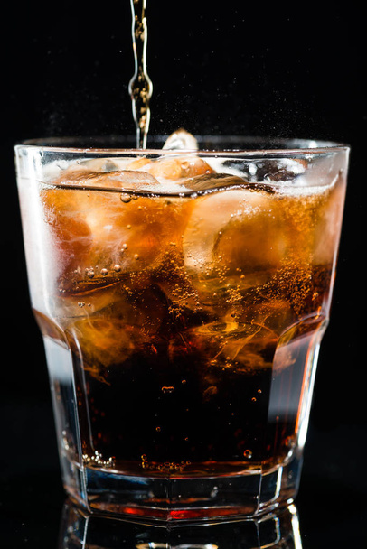 stream of cola is poured into a glass with ice - Zdjęcie, obraz