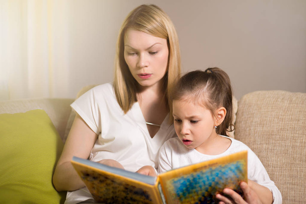 Bardzo piękne matka i jej córka są czytanie książki. - Zdjęcie, obraz