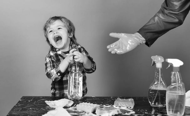 Cleaning concept. Kid with laughing face holds spray on table. - Foto, afbeelding
