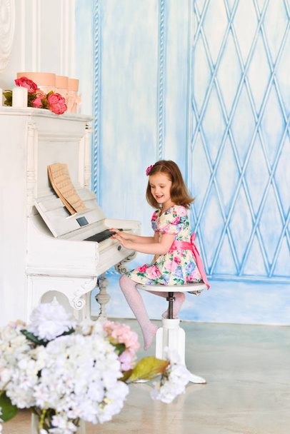 little girl in white dress playing the piano. Music and art concept. - Foto, Bild