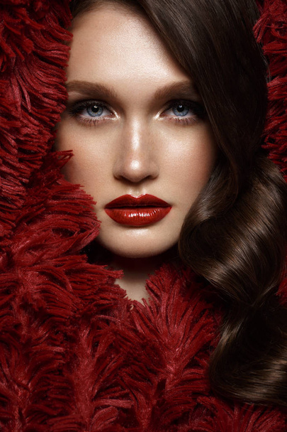 A beautiful girl with evening make-up, a curls wave and red lips. Beauty face. - Photo, Image