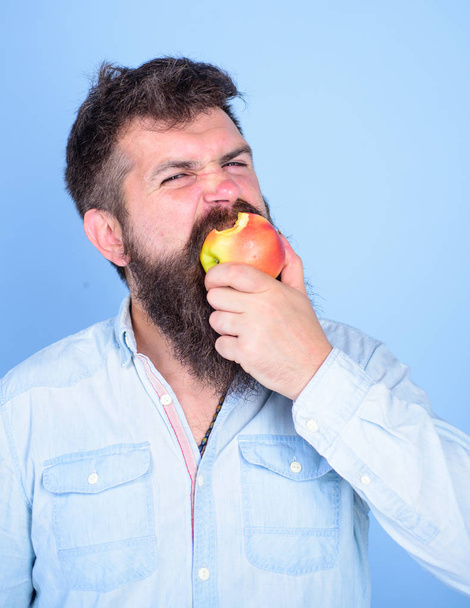 Man handsome hipster with long beard eating apple. I love apples Man diet nutrition eats fruit. Hipster hungry bites juicy ripe apple. Fruit healthy snack always good idea. Healthy nutrition concept - 写真・画像