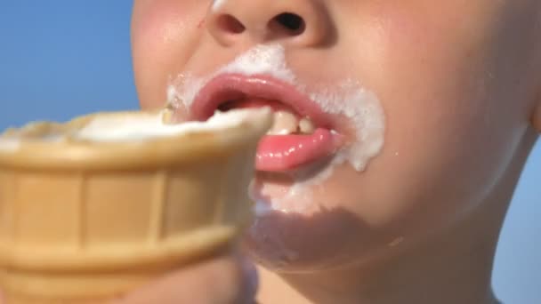 Un ragazzino affamato che mangia gelato sulla spiaggia del mare. Il viso dei bambini è imbrattato di gelato
. - Filmati, video