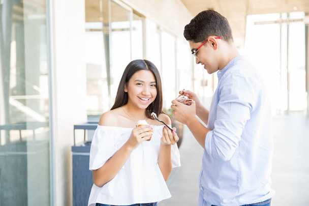 Szczęśliwa para nastoletnich o dacie i jeść lody w centrum handlowym - Zdjęcie, obraz