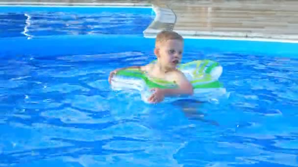 Kleine jongen drijven op opblaasbare cirkel in het blauwe zwembad. - Video