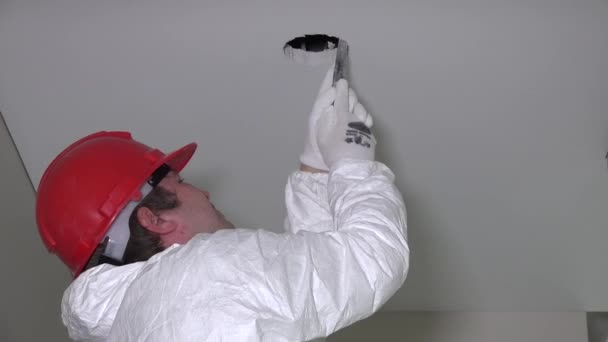 Profesjonalny pracownik człowiek podziurawić sufit kartonowo-gipsowych do instalacji oświetlenia i schodzić z drabiny. Pomniejszyć strzał. 4k Uhd - Materiał filmowy, wideo