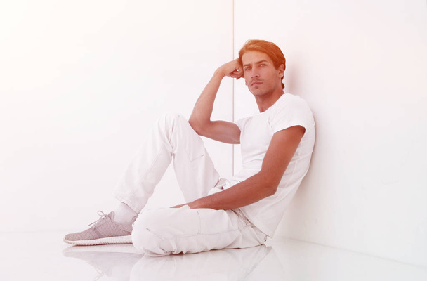 anxious man sitting beside a white wall - Foto, Imagem