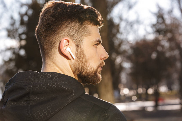 Close up of a confident young sportsman in earphones outdoors - Fotó, kép