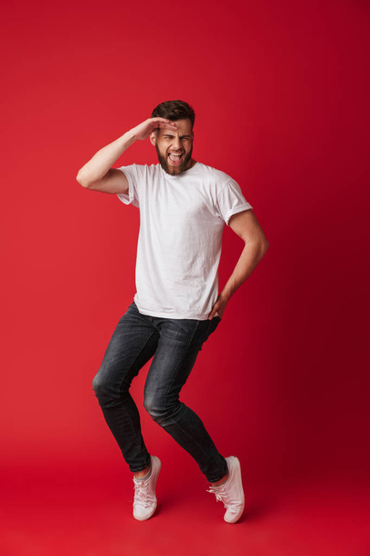 Photo of handsome young man dancing isolated over red wall background. - Foto, Imagem