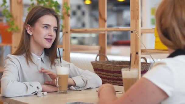 Dwie młode kobiety rozmawiają i piją kawę siedząc w kawiarni. - Materiał filmowy, wideo