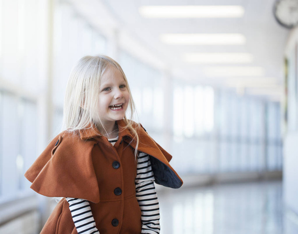 Portrait of laughing little girl wearing fashionable orange coat - Foto, Bild