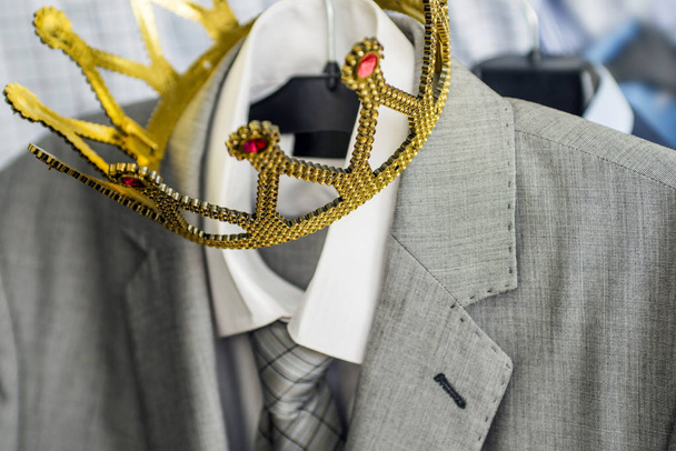 Traje de negocios con una corona de oro colgando de una percha. La ropa es una persona exitosa. Concepto de negocio. Metáfora
 - Foto, Imagen
